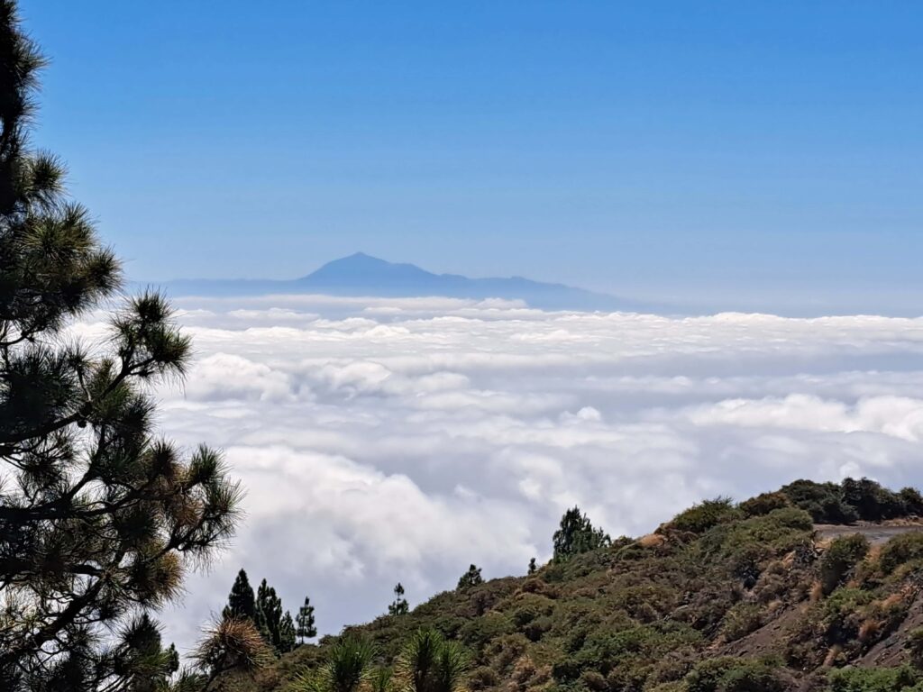 Wolkengebilde ueber Land mit Berggipfel im Hintergrund
