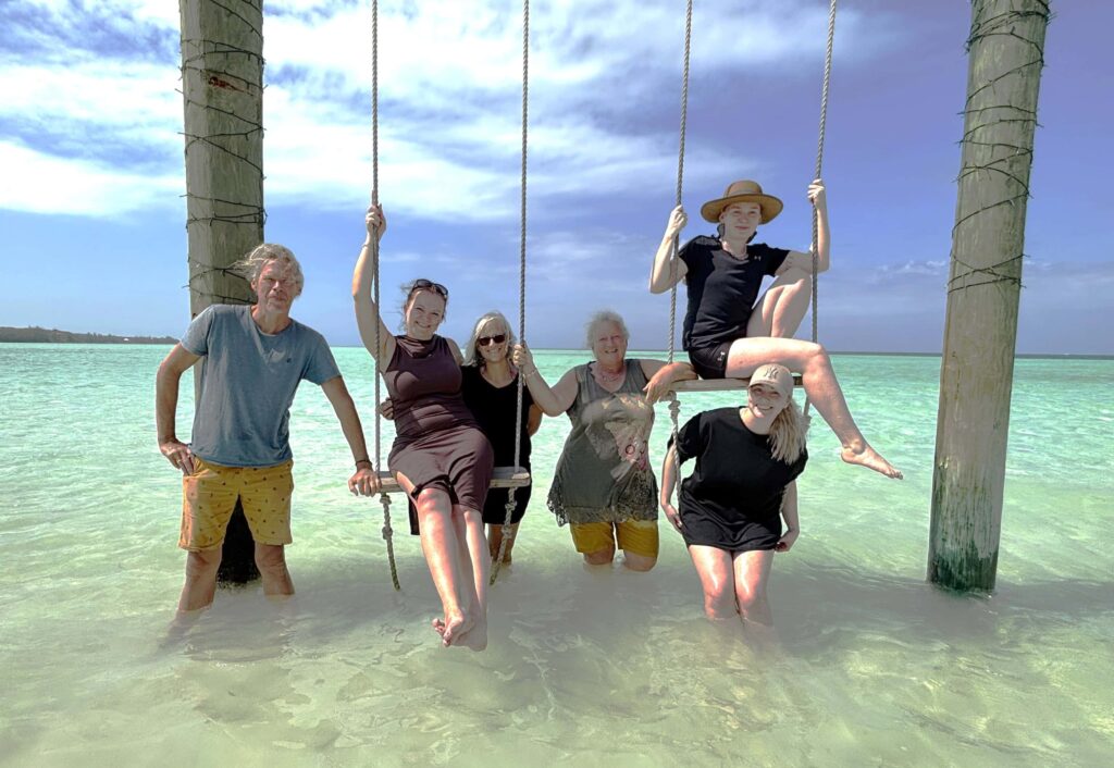 Bahamas Crew der Blue Joline am traumhaften Bahama Strand. Das Wasser ist warm die Schaukel eine schöne Abwechslung und Fotomotiv für ein Crewfoto.