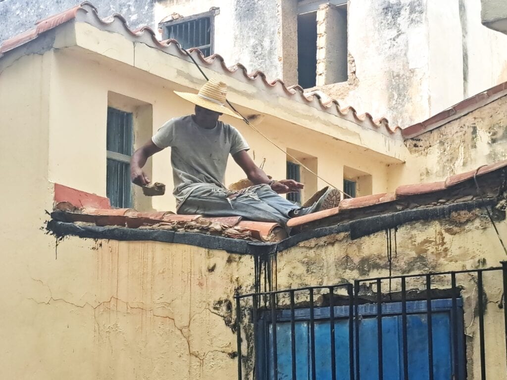Dieser junge Kubaner setzt Dachziegel in Beton - bedauerlicherweise wird seine Arbeit kurze Zeit später von wolkenbruchartigen Regenfällen zu nichte gemacht